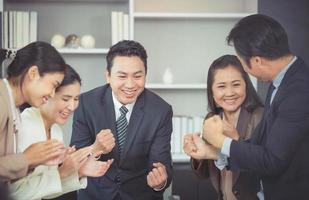 equipo de negocios emocionado celebra la victoria corporativa juntos en la oficina, el equipo celebra el éxito ganar conceptos de trabajo en equipo de poder de asociación foto