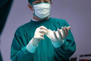 cirujano masculino con guantes de protección médica y mascarilla quirúrgica en el quirófano del hospital, equipo médico que realiza una operación quirúrgica en el quirófano foto