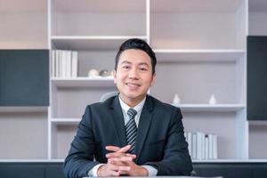 Smiling business man sitting at office desk and looking at camera photo