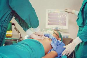 Patient on bed with medical team performing surgical operation in operating room photo