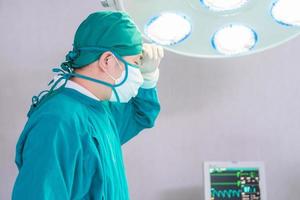 Male surgeon wearing surgical mask in operation theater at hospital, doctor in operating room photo