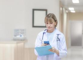 Female doctor using mobile smartphone and holding medical reports at hospital, Medical healthcare and doctor service photo