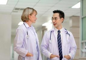 Medical team discussing in the corridor at hospital, team of mixed-races doctors, Group of multi ethnic medics, men and women talking and having discussion photo