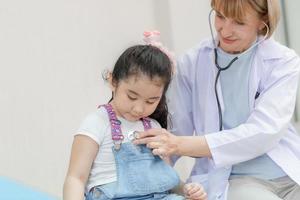 doctora examinando a una niña linda con estetoscopio, niña en consulta con el pediatra. conceptos de salud y medicina foto