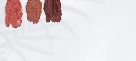 The texture of the lipsticks in nude and dark shades on a white background and copy space. photo