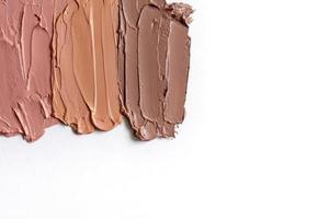 The texture of the lipsticks in nude shades on a white background and copy space.