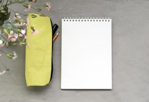 An empty notebook, a pencil case, and flowers on a gray background. Template with copy space. photo