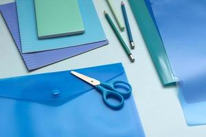 Background with blue office supplies. Folder, notebook, notebook, pencil in different shades of the same color. photo