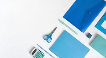 Blue green stationery in the corner and copy space. Accessories for writing and counting on a white table, a notebook, a ruler, scissors, a pencil, a pen. photo