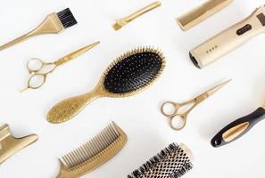 fondo con herramientas de peluquería doradas. accesorios de peluquería, peine, tijeras en blanco foto