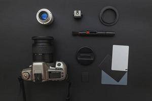 Photographer workplace with dslr camera system, camera cleaning kit, lens and camera accessory on dark black table background. Hobby travel photography concept Flat lay top view copy space photo