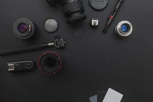 lugar de trabajo del fotógrafo con sistema de cámara dslr, kit de limpieza de cámara, lente y accesorio de cámara sobre fondo de mesa negro oscuro. concepto de fotografía de viajes de hobby. espacio de copia de vista superior plana. foto