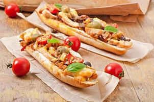 Big sandwich with roasted vegetables and chicken with cheese and basil on old wooden background photo