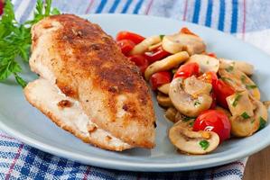 Chicken fillet in crispy breadcrumbs garnished with mushrooms and tomatoes photo