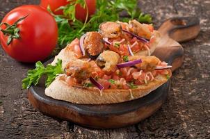 Bruschetta with mussels, cheese and tomatoes photo