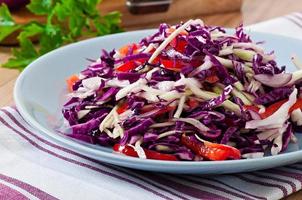 ensalada de col roja y blanca y pimiento rojo dulce, sazonada con jugo de limón y aceite de oliva en un tazón de madera foto