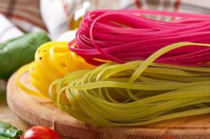 Colorful fettuccine  pasta and cooking ingredients on wooden table photo