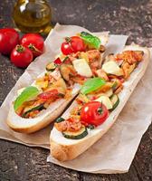 Big sandwich with roasted vegetables  with cheese and basil on old wooden background photo