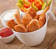Chicken nuggets with sauce and vegetables photo