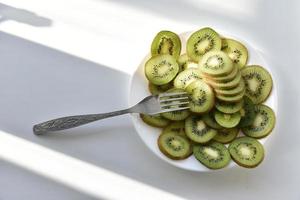 Kiwi fruit slices on a white plate with a fork photo