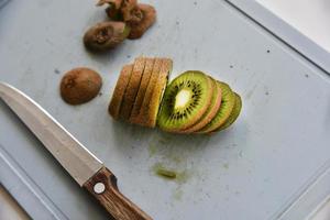 Slicing kiwi fruit with a knife on a board photo