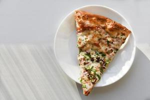 Triangular slice of pizza on a white plate photo
