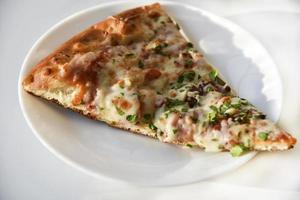 Triangular slice of pizza on a white plate photo