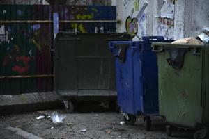 contenedores de basura y bolsas con basura en la calle