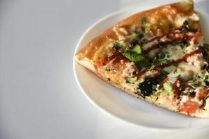 Triangular slice of pizza on a white plate photo