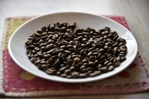 granos de café tostados en un plato blanco foto