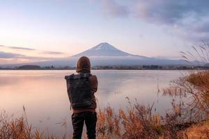 Asian young man stand looking Mount Fuji on Kawaguchiko Lake at dawn