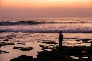 Silhouette young woman take a photo with beautiful sea on coastline