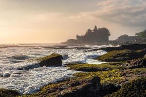 Ancient Tanah Lot temple on rocky mountain at coastline photo