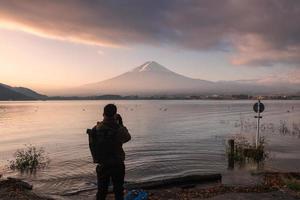 Man backpacker taking a photo with fuji-san in Kawaguchiko lake