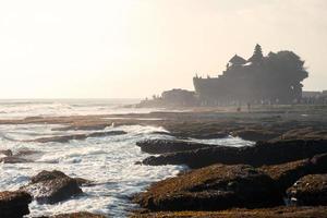 antiguo templo de tanah lot en la montaña rocosa en la costa foto