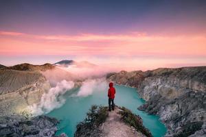 Man standing on edge of crater with colorful sky at morning photo