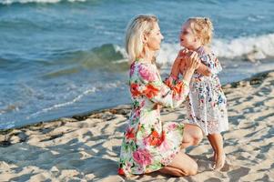 Mother and beautiful daughter having fun on the beach. Portrait of happy woman with cute little girl on vacation.
