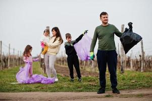 Family with trash bag collecting garbage while cleaning in the vineyards . Environmental conservation and ecology, recycling. photo