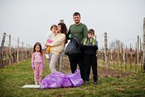 familia con bolsa de basura recogiendo basura mientras limpia en los viñedos. conservación ambiental y ecología, reciclaje.