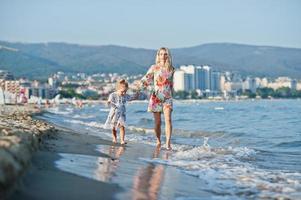 madre e hija hermosa divirtiéndose en la playa. retrato de mujer feliz con linda niña de vacaciones. foto