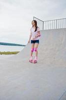 retrato de una fabulosa mujer joven patinando en la pista de patinaje al aire libre. foto