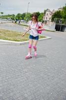 retrato de una joven guapa con ropa informal patinando en la acera del parque. foto