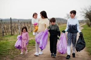 Family with trash bag collecting garbage while cleaning in the vineyards . Environmental conservation and ecology, recycling.