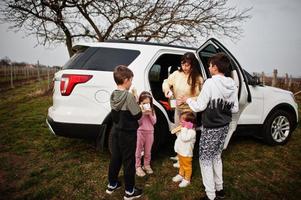 Mother with kids drink tea outdoor near white suv car. photo