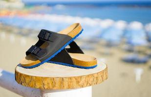 azul con sandalias de hombre negro sobre un tronco de madera en verano foto