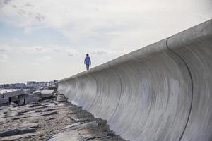 niño caminando sobre un muro de piedra en la playa foto