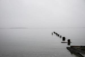 viejo muelle hundido en el océano en un día de niebla foto