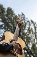 las manos tocan la guitarra al aire libre durante el día foto