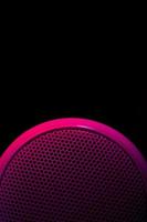 Musical speaker illuminated with lilac crimson on a black background. Vertical background. photo