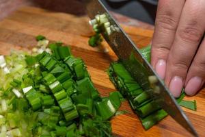 Cutting green onions with a knife on a kitchen board. photo